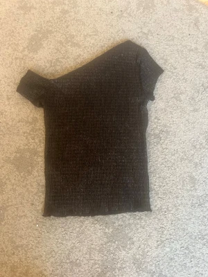 Svart offshoulder topp med glitter från hm - Säljer en svart offshoulder topp med glittriga detaljer. Toppens material är ribbad som ger en cool look. Perfekt för dig som vill sticka ut lite extra. Passformen är tight och den är kortärmad. Perfekt till nyår och till en festligare look💓💓 använd få gånger 
