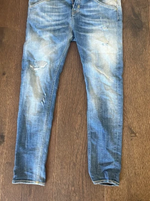 Blå slitna skinny jeans - Säljer ett par blå skinny jeans med slitningar och tvättade detaljer. Jeansen har klassisk femficksmodell och smal passform. Perfekta för en avslappnad och trendig look.