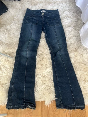 Mörkblå bootcut jeans - Säljer ett par mörkblå lågmidjade bootcut jeans. De är uppsprättade nedtill så att de passar mig som är runt 1,67. Jeansen har två stora fickor fram och dubbla knappar i midjan. Snygg tvätt och cool vintagekänsla, perfekta till sneakers eller boots. Storlek 158 (barnavdelning) men passar även xs eller liten S. 