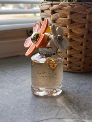Daisy Ever So Fresh parfym Marc Jacobs - Daisy Ever So Fresh parfym från Marc Jacobs i en genomskinlig glasflaska med dekorativ kork prydd med stora blommor i orange, vitt och guld. Flaskan har en elegant och lekfull design som verkligen sticker ut på hyllan. 30ml. Använd enstaka gång 