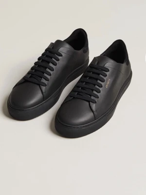 Svarta sneakers från Axel Arigato - Stilrena svarta sneakers från Axel Arigato i slätt läder med matchande svarta skosnören och diskret guldfärgad logga på sidan. Klassisk låg modell med minimalistisk design och svart sula. Perfekta för en clean och modern look. Köpta online på arigatos hemsida, orderbekräftelse samt digitalt kvitto finns 
