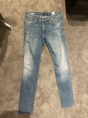 Ljusblå skinny/mer slim jeans jackjones - Säljer ett par ljusblå ä jeans från  Jean med slitningar och små hål på låret. Jeansen har klassisk femficksdesign, normal midja och är tillverkade i mjuk denim. Perfekta för en avslappnad och trendig look. Storlek 31:32 och sitter mer som slim.