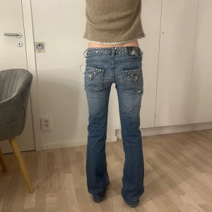 Blå lågmidjade bootcut jeans med pärlor  - Kan diskutera pris!!, Snygga blå jeans med låg midja och bootcut passform. Jeansen har coola pärlor  och pärldetaljer på både linning och bakfickor, samt klassisk femficksdesign. Perfekta för dig som vill sticka ut med en unik och trendig look.