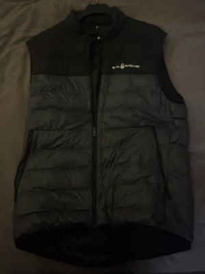 Svart dunväst från Sail Racing - Snygg svart dunväst från Sail Racing med hög krage och dragkedja framtill. Säljer denna då den inte kommer till användning, är det några funderingar så är det bara att höra av sig :)