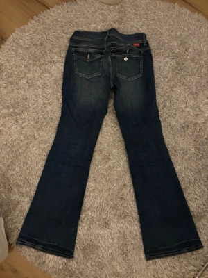 Bootcut jeans - Säljer ett par supersnygga mellanblå jeans med knappar på bakfickorna💕