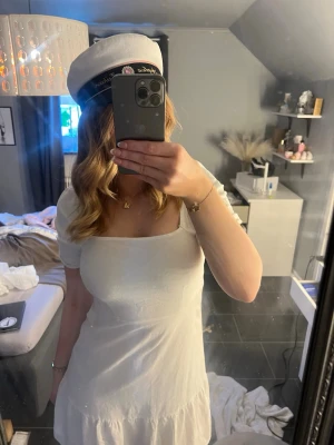 Vit kort klänning med puffärm - Säljer en söt vit kort klänning med puffärmar och fyrkantig ringning. Klänningen har en flowy kjol och är perfekt för student eller sommar. Materialet känns lätt och luftigt, troligen bomull eller polyester. Enkel och stilren design utan mönster.