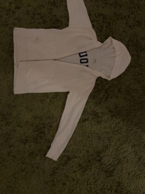 Vit hoodie med dragkedja - En Zadig Voltaire zip up med stor text amour på bak sidan. Tröjan är perfekt för höst- sommar väder och är otroligt bekväm. Tröjan har nära till inga defekter alls och är i bra skick. Nypris gör för runt 4000kr och är i storlek S