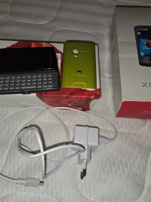 Sony Xperia Android-telefon grön - Säljer en Sony Xperia Android-telefon i en unik grön färg med QWERTY-tangentbord och tillhörande laddare. Telefonen har en kompakt design och bakstycket är gjort i plast. Perfekt för dig som gillar fysiskt tangentbord och smidig mobil.