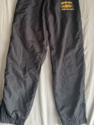 Corteiz byxor - Svarta tränings/vind byxor från corteiz. Storlek M på byxorna. Har en liten dragkedja vid fötterna ungefär där man kan dra upp de för att få de att bli ”större” vid fötterna. Har använts 2 ggr.