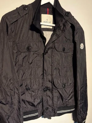 Moncler field jacket str S - Hej! Säljer nu en Moncler field jacket i str S Denna funkar perfekt för dig som vill ha en vindtålig jacka och en som är stilren och passar till många olika sortiment. Jackan kommer i 9/10 skick saknar däremot en diskret knapp däför säljer ka jackan för det här priset säljer endast för 1299kr ny pris 6000 Hör av er vind minsta lilla fråga!😊