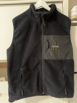AIK fleeceväst - Svart fleece/pile väst från AIK Hockey i storlek L. Passformen längst ner i originalvaran var lite för lång så den är som man kan se på bild 3 lite insydd på insidan på ena sidan för en perfekt längd och passform. 