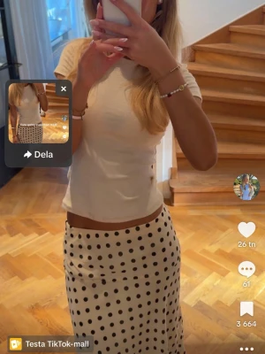 Vit prickig långkjol från H&M - Säljer en vit långkjol från H&M med svarta prickar. Kjolen har en rak och flowy passform som ger en chill vibe och är perfekt för vår och sommar. Materialet känns lätt och bekvämt, vilket gör den enkel att styla med olika toppar.