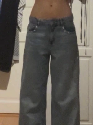 Intressekoll! Vida blå jeans med låg midja - Säljer ett par blå jeans med låg midja och vida ben. Jeansen har klassisk femficksdesign och är tillverkade i denim. Har studs vid på sidan och längst med rumpan. Perfekta för en avslappnad och trendig look. Köp inte dennna annons utan skriv till mig först, lägg rimliga bud, nypris 499 kr från Gina tricot 💕