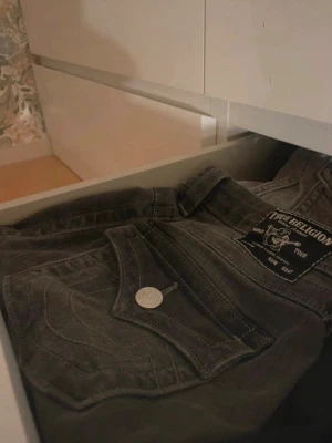 Gråa True Religion jeans - Säljer ett par grå bootcut jeans från True religion i mid Rise men om man är lite längre passar dom som low waist! Säljer pågrund av att dom är för långa i benen!💕 storlek W26