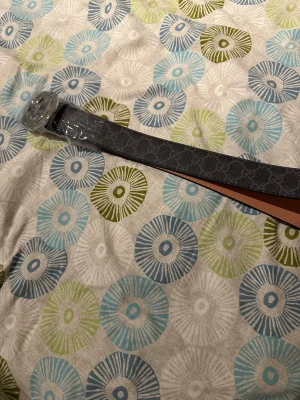 Svart bälte med GG-spänne - Snyggt svart bälte med klassiskt GG-mönster längs hela remmen och ett stort, runt GG-spänne i silverfärg. Helt ny 