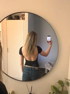 Svart croppad topp med öppen rygg - Säljer en svart croppad topp med korta ärmar och en djup öppen rygg. Materialet känns mjukt och stretchigt, vilket gör den bekväm att bära.