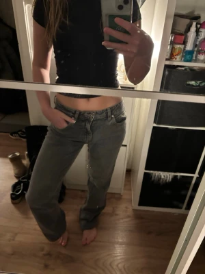 Gråa raka jeans med låg midja - Säljer ett par gråa jeans med rak passform och låg midja. Jeansen har klassisk femficksdesign och är tillverkade i ett mjukt denimtyg. Perfekta för en avslappnad och trendig look.