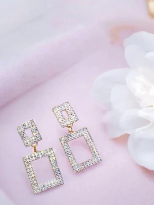 Guldiga rektangulära örhängen med strass - oanvända  - Säljer ett par statement örhängen i guldton med dubbla rektangulära former täckta av gnistrande strass. Örhängena har en modern och trendig design som verkligen drar blickarna till sig. Perfekta för dig som vill sticka ut med accessoarer. - Då jag själv gör dom får man nya och oanvända 
