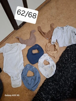 Babypaket med bodies och dregglisar - Säljer ett paket med babykläder i storlek 62/68. Innehåller vita och ljusblå bodies, långärmad tröja i ljusgrått samt flera dregglisar i blått, beige och vitt med tryck. Perfekt för småbarnsföräldrar som vill ha ett praktiskt set.