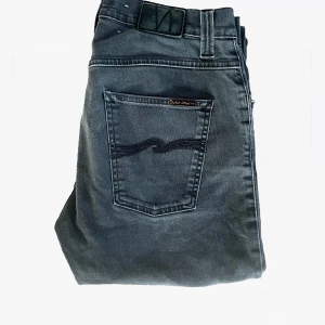 Nudie jeans Grim Tim  - Säljer ett par schysta nudie jeans i modellen Grim Tim. Dem har börjat bygga på sig riktigt snygga slitningar och bortsett från den i riktigt fint skick. Storleken är 33/34.   Pris 599 Skick 8,7/10 Storlek 33/34  Mått 📏  Midja 41cm  Längd 108cm Benöppning nere 18cm  Hör av er vid minsta lilla!