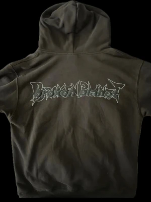 Svart Broken Planet hoodie  - Cool svart (hade sagt mörk grå) hoodie från Broken Planet med stor grafisk text på ryggen och flera tryck på framsidan, inklusive 'BEWARE', figurer och stjärnor. Har huva och magficka samt tryck på ena ärmen. Perfekt för dig som gillar streetwear och unika detaljer. Använd bara en gång med inga skavanker, hål eller fläckar.   Pris kan diskuteras vid snabbt köp 💬  Skickas inom 24h ( om jag inte är upptagen)🔜 Skriv gärna ifall ni har frågor 