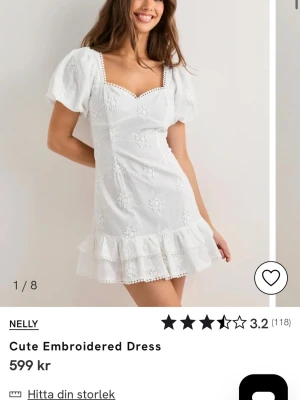 Vit broderad kortklänning från Nelly - Söt vit kortklänning från Nelly med broderade blommor, puffärmar och volangkant nertill. Klänningen har fyrkantig ringning, öppen rygg med knyt och dekorativa spetsdetaljer. Perfekt för sommarens alla tillfällen. Aldrig använd. 
