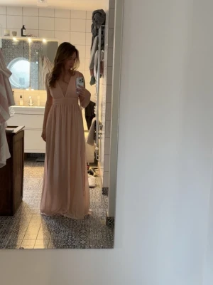 Ljusrosa långklänning med v-ringning - Säljer denna balklänning då den inte kom till användning tyvärr. Oanvänd med prislappen kvar. ljusrosa långklänning med djup v-ringning och markerad midja. Nypris; 1250kr