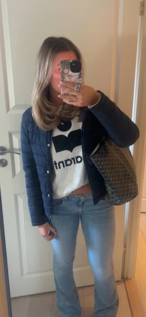 Svart quiltad vindjacka - Snygg svart quiltad vindjacka med tryckknappar framtill. Jackan har en klassisk, rak passform och lätt vaddering som gör den perfekt för vår och höst. Tidlös design som funkar till det mesta och är enkel att styla.