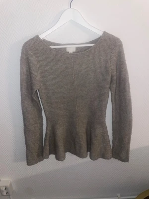 Beige ribbstickad tröja H&M - Säljer en beige ribbstickad tröja från H&M med lång ärm och lätt utsvängd nederkant. Tröjan har rund halsringning och är i mjukt material, perfekt för lager på lager under kyliga dagar.