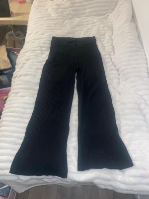 Svarta ribbade leggings från Even&Odd - Säljer ett par svarta ribbade leggings från Even&Odd med hög midja och utsvängda ben. Materialet är stretchigt och bekvämt, perfekt för dig som gillar en trendig och avslappnad look. Passar till många olika outfits och är riktigt snygga.