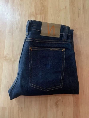 Nudie jeans  - Mörkblåa jeans från nudie jeans i modellen skinny lin. Midja 32cm, längd 101cm. JAG SKICKAR EJ FLER BILDER NÄR JAG BÄR JEANSEN! för bättre inblick i passformen rekommenderar jag att googla på modellnamnet. För storleksguide kolla måtten noggrant då jeansen alltid kan vara uppsydda heller krympta och jag ej tar emot returer :) s6,3