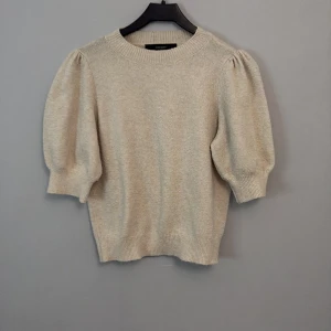 Beige stickad tröja från Vero Moda - Säljer en stilren beige stickad tröja från Vero Moda. Tröjan har trekvartsärmar med puffiga axlar och ribbade muddar. Perfekt för en mysig dag🫶🏼