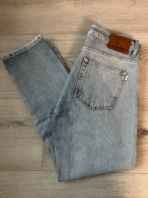 Ljusblå raka jeans från Woodbird - Säljer ett par ljusblå jeans från Woodbird med klassisk femficksdesign och raka ben. Perfekta för en avslappnad och trendig look.