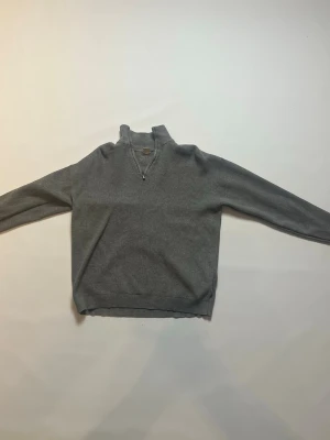 Grå halvzip tröja i bomull från Lindex storlek 158-164 - En stilren grå tröja med halv dragkedja och hög krage. Tillverkad i mjuk bomull, perfekt för lager på lager. Långärmad modell med ribbade muddar och enkel design som passar till det mesta. Den är från Lindex och storleken är 158-164