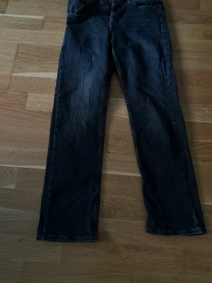 Svarta jeans från Replay - Säljer ett par svarta jeans från Replay med klassisk femficksdesign och raka ben. Jeansen har en stilren look och är tillverkade i denim. Perfekta för dig som gillar en enkel och tidlös stil.