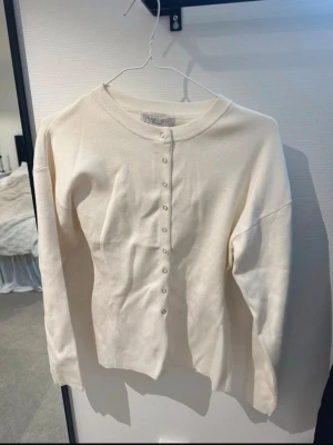 Vit figursydd kofta  - Vit kofta med knappar, aldrig använd. Färgen är off white