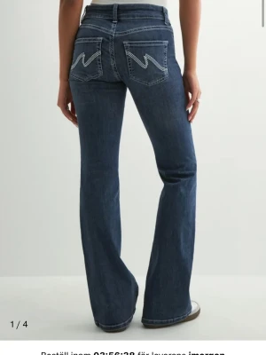 Blå bootcut jeans från Nelly - Säljer ett par klassiska blå bootcut jeans från Nelly med ikoniska vita sömmar på bakfickorna. Jeansen har låg midja. Perfekta för en avslappnad och trendig look. Skriv om ni vill ha egna bilder eller har andra frågor!🥰(dem är avklippta ca 5 centimeter längst ner på benen)