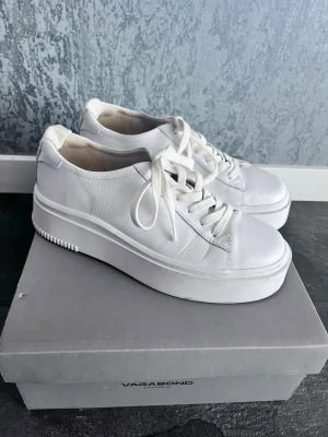 Vita platåsneakers från Vagabond - Stilrena vita sneakers från Vagabond med platåsula och klassisk snörning. Skorna är tillverkade i slätt läder och har en chunky siluett som ger extra höjd. Perfekta för dig som gillar minimalistisk och trendig stil.