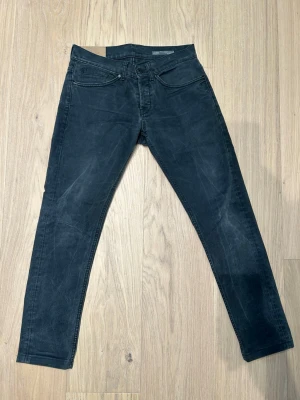 Svarta slim fit jeans från dondup - Säljer ett par svarta slim fit jeans från dondup. Jeansen har diskreta slitningar. Perfekta för en avslappnad och trendig look.