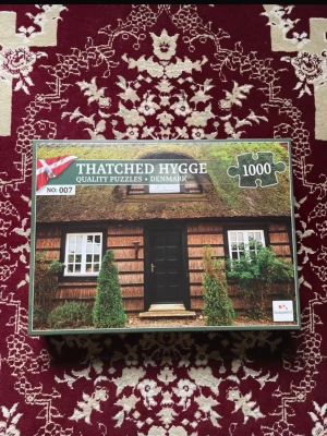 Thatched Hygge 1000-bitars pussel - Säljer ett 1000-bitars pussel från Thatched Hygge med motiv av ett danskt hus med halmtak och gröna växter.  Perfekt för dig som gillar utmanande pussel.