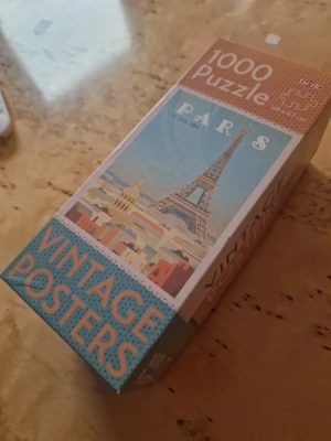 Vintage Paris pussel 1000 bitar - Säljer ett komplett vintageinspirerat pussel från Tactic med 1000 bitar. Motivet föreställer Eiffeltornet i Paris i pastellfärger och retrostil. Pusslet mäter 48 x 67 cm när det är klart och kommer i en snygg förpackning med texten 'Vintage Posters'. Perfekt för dig som gillar Paris och pussel.