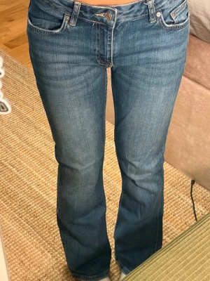 Blå bootcut jeans med låg/mid midja🌸 - Säljer ett par klassiska blå bootcut jeans. Jeansen har en snygg tvätt och subtila slitningar framtill. Tillverkade i stretchigt denimtyg för skön passform. 