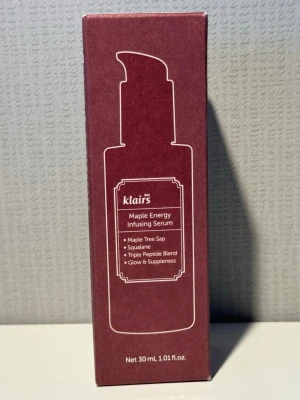 Klairs Maple Energy Infusing Serum - Klairs Maple Energy Infusing Serum är ett ansiktsserum i en vinröd kartong med vit text. Innehåller lönnträdssaft, squalane och trippelpeptidblandning som ger glow och spänst till huden. Förpackningen är stilren och rymmer 30 ml.