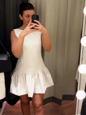 Klänning med öppen rygg och volang nedtill, Bik Bok - Säljer en superfin vit kort klänning med öppen rygg från Bik Bok.  Klänningen stängs med en ”osynlig” dragkedja baktill och har en figurnära passform med en volang nedtill.  (Använd endast 1 gång vid ett kort tillfälle) 