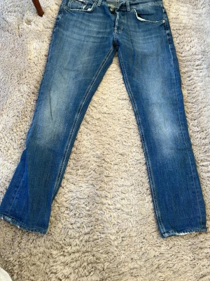 Dondup Ritchie  - Säljer ett par klassiska blå jeans med raka ben och lätt slitna detaljer. Jeansen har fem fickor, normal midja och kontrastsömmar. Perfekta för en avslappnad och trendig look. Materialet är denim i bomull. Storlek 32.