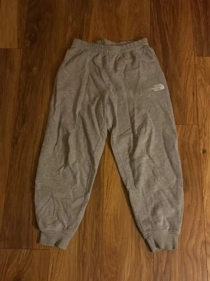 Grå mjukisbyxor från The North Face - Säljer ett par grå mjukisbyxor från The North Face med broderad logga på vänster lår. Byxorna har resår i midjan. Tillverkade i mjukt material. Finns ett par likadana i svart i min profil, man kan köpa ett par för 75kr eller båda för 130kr!