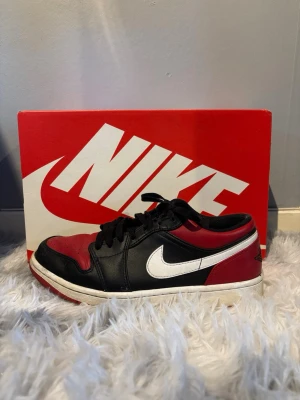 Nike Air Jordan 1 Low Bred 41 - Snygga Nike Air Jordan 1 Low sneakers i svart, rött och vitt läder. 