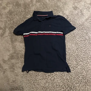 Pike skjortor - Fyra Pikeskjortor från Bland annat Tommy Hilfiger. En marinblå med vita och röda detaljer samt logga på bröstet, en i enkel grön färg och två mörkblåa. Alla har klassisk krage, knappar framtill och korta ärmar. Tillverkade i mjuk bomull för skön känsla. 1=100kr, 2= 25kr, 3= 25kr, 4= 100kr, Alla=200kr