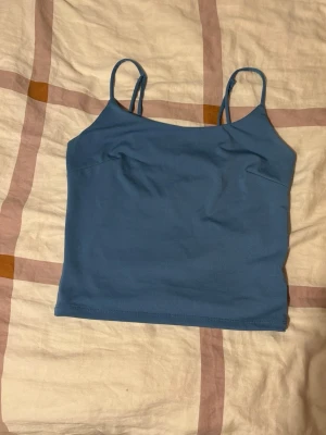 Blått linne från Bik Bok  - Snyggt blått linne med tunna axelband och rak passform. Tillverkat i ett stretchigt och mjukt material som sitter skönt på kroppen. Använd ett fåtal gånger bara, och är i storlek S