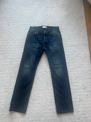 Balenciaga Indigo Denim - Säljer ett par mörkblå jeans från Balenciaga med rak passform. Jeansen har snygga slitningar och är tillverkade i denim med en cool tvätt. Jeansen är 109cm (L34) långa så dom passar för dig som är 178-185. Dom var helt nya när jag köpte dom och har använt dom max 3 gånger. Retail ligger på 1000$+. Hör av dig om du har fler frågor. 